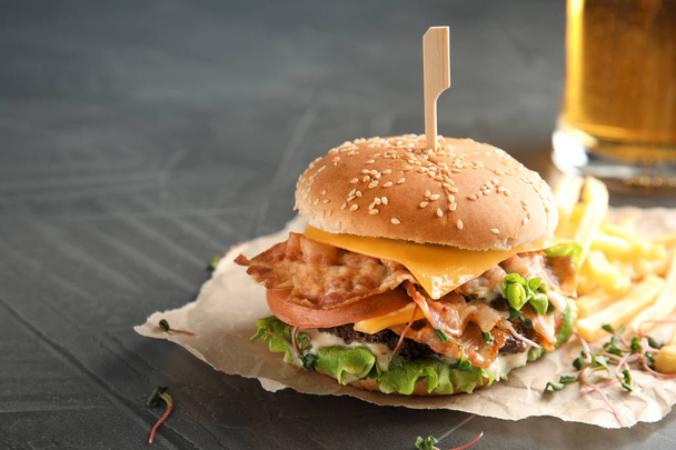 Tasty burger with bacon on table. Space for text - Photo, image