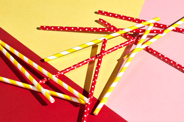 colorful plastic drinking straws isolated over the pink, yellow, red background - Foto, afbeelding