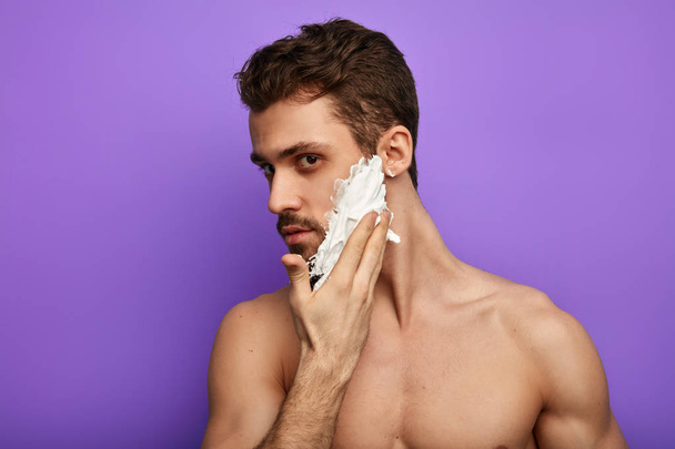 gorgeous man applying shaving cream on his face - Foto, Imagem