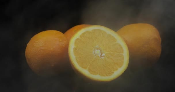 Fruta tropical naranja en hielo frío nubes de humo de niebla sobre fondo negro
 - Metraje, vídeo