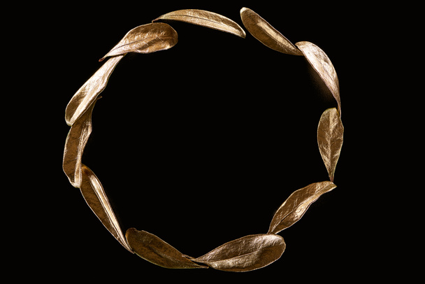 vista dall'alto di cerchio in metallo dorato foglie decorative isolate su nero con spazio copia
 - Foto, immagini