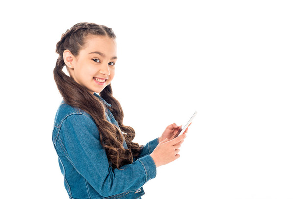 szczęśliwy dzieciak w kurtka dżinsowa za pomocą smartfona na białym tle - Zdjęcie, obraz