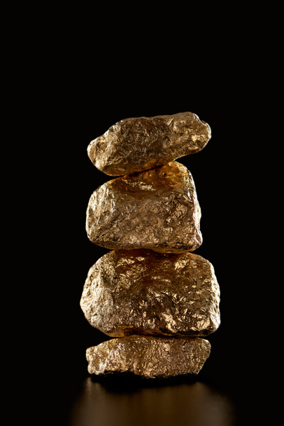 stack of gold textured shiny stones isolated on black - Photo, image
