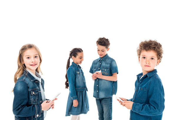 beyaz izole akıllı telefonlar kullanarak denim giysiler dört çocuk - Fotoğraf, Görsel