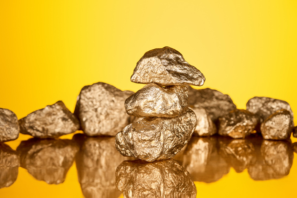 selective focus of three gold shiny stones with reflection isolated on yellow  - Zdjęcie, obraz
