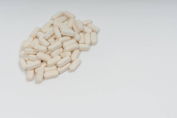 White pills on white background. Dietary supplements in the form of tablets. Vegan Glucosamine tablets. - 写真・画像