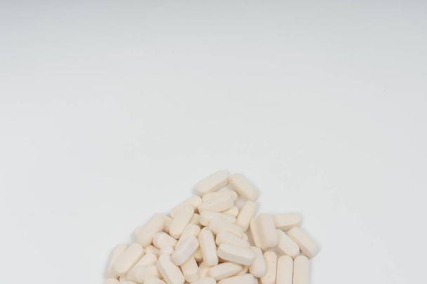 White pills on white background. Dietary supplements in the form of tablets. Vegan Glucosamine tablets. - Photo, image