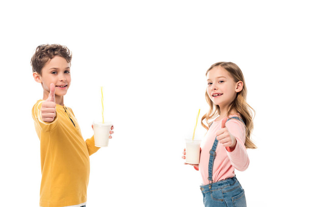 dos niños sosteniendo batidos y mostrando los pulgares hacia arriba aislados en blanco
 - Foto, imagen