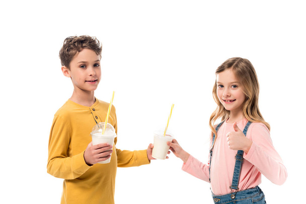 two kids holding milkshakes and showing thumb up isolated on white - Foto, Imagem