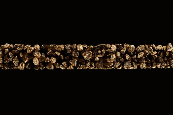 Ansicht von goldenen strukturierten Steinen in horizontaler, enger Reihe isoliert auf schwarz - Foto, Bild
