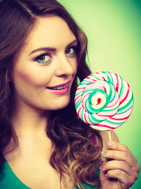 Smiling girl with lollipop candy on green  - Фото, изображение