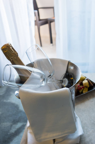 テーブルの上のシャンパンとフルーツのバケツ - 写真・画像