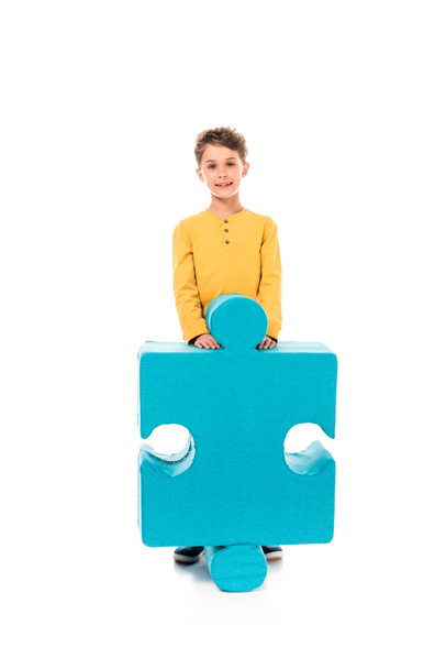 Ganzkörperansicht eines lächelnden Kindes mit großem Puzzle auf weißem Hintergrund - Foto, Bild