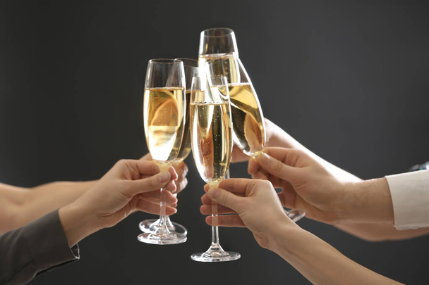 People clinking glasses of champagne on dark background, closeup - 写真・画像