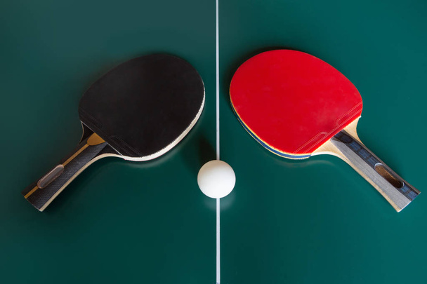 dwa rakiety do tenisa stołowego i piłka na zielonym stole.  - Zdjęcie, obraz