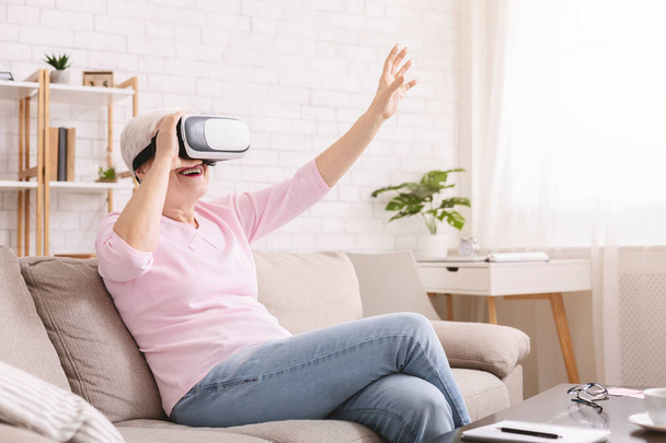 Modern senior woman using VR glasses at home - Foto, Imagem