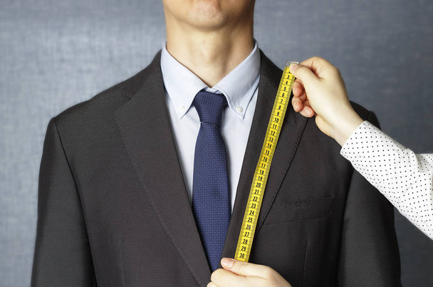 The tailor measures the suit with a measuring tape close-up - Photo, Image