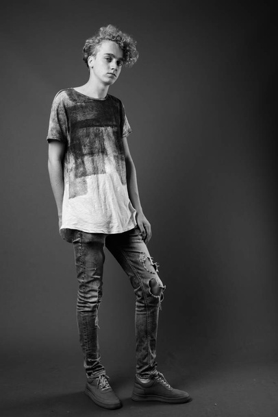 Skinny jeune homme aux cheveux bouclés sur fond gris en blac
 - Photo, image