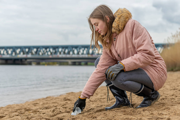 Mujer está limpiando la playa de residuos plásticos a mano
 - Foto, imagen