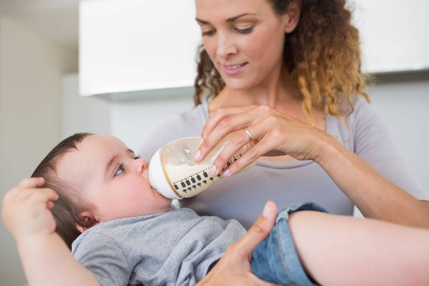 Mother feeding milk to cute baby from bottle at home - Foto, Bild