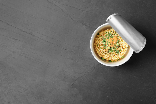 Cup of instant noodles on grey background, top view. Space for text - 写真・画像