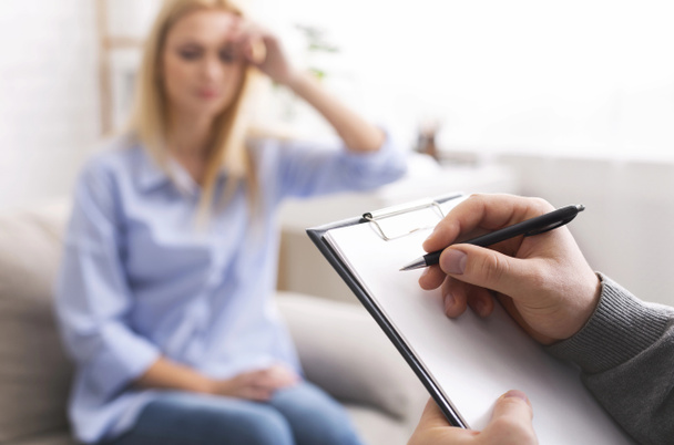 Καταθλιπτική γυναίκα που μιλάει με ψυχοθεραπευτή, ο γιατρός λαμβάνει σημειώσεις - Φωτογραφία, εικόνα