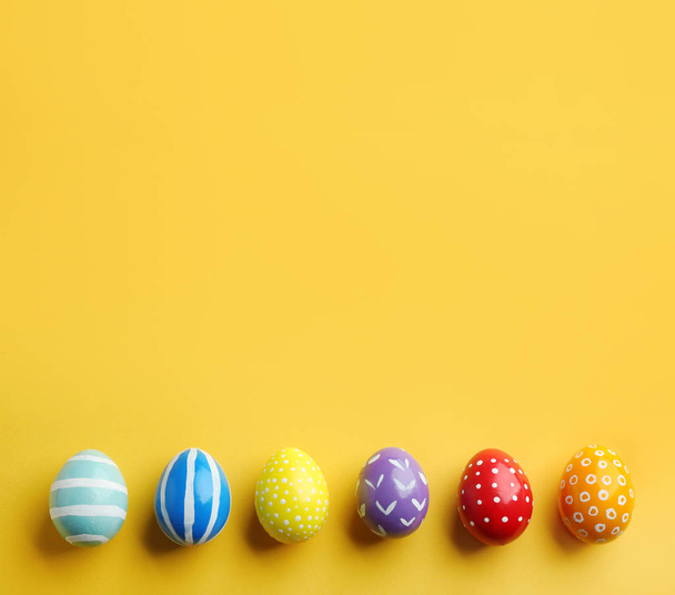 Flat lay composition of painted Easter eggs on color background, space for text - Fotoğraf, Görsel