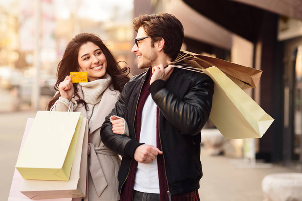 Shopping together. Woman showing credit card to husband - Foto, afbeelding