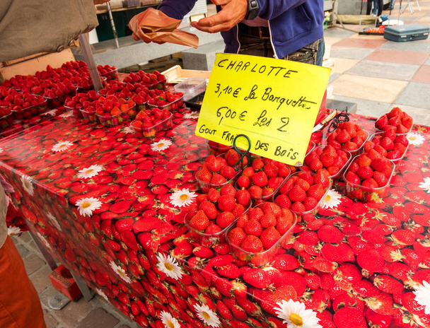 Ein Bauer verkauft auf einem Markt frische Erdbeeren auf einer Tischdecke im Erdbeermuster. Cherbourg, Normandie, Frankreich - Foto, Bild