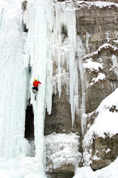 Ice climber struggles up a frozen waterfall. - Photo, Image