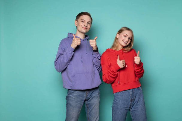 Счастливые друзья мальчик и девочка в повседневной одежде, показывая большие пальцы вверх и глядя в камеру
 - Фото, изображение