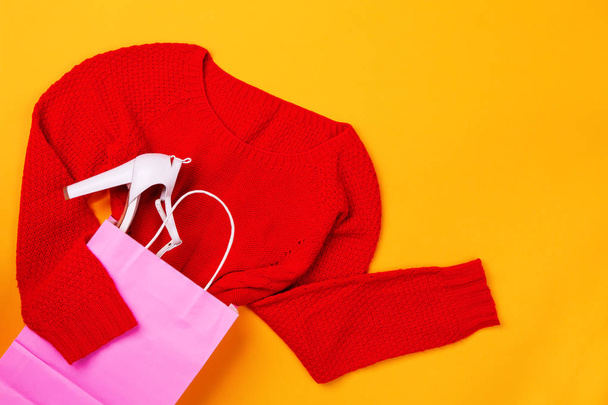Вид сверху розовой сумки для покупок с красным свитером и стильной обувью
 - Фото, изображение