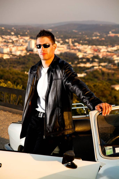View of a young male with a jacket next to his white convertible car. - Foto, Imagen