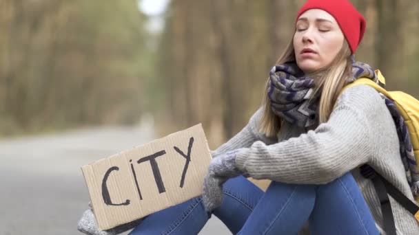 Chica autoestop sentarse en el camino vacío en madera con cartel de la ciudad, coche sin parar
 - Imágenes, Vídeo