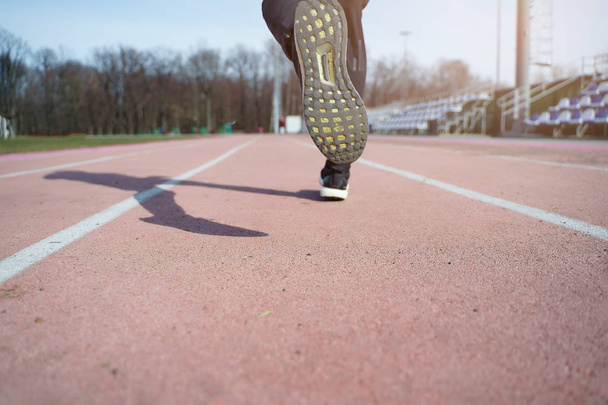 Image from back of legs of athlete running through stadium - Foto, Imagen