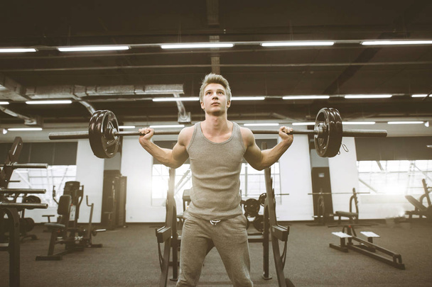 Fit and ripped man lifting weights in the gym. Gym lifestyle concept. Athletic man exercising with barbell at gym - Photo, Image