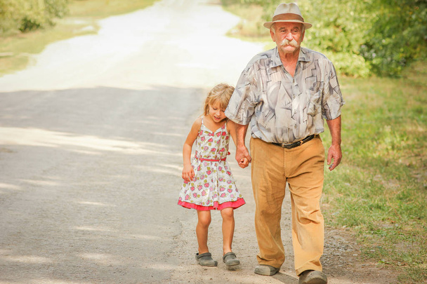 šťastný dědeček kráčí s dítětem na své cestě do parku - Fotografie, Obrázek
