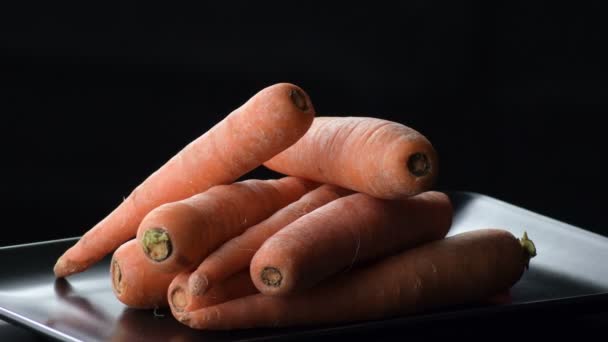 Zanahorias naturales girando en una bandeja negra. Daucus carota
 - Imágenes, Vídeo