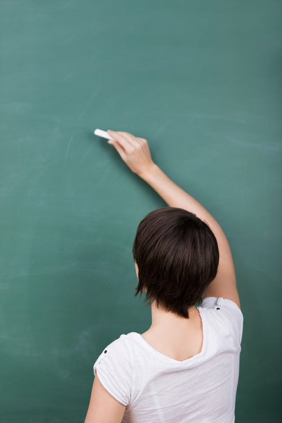 Student writing on blackboard - Foto, Bild