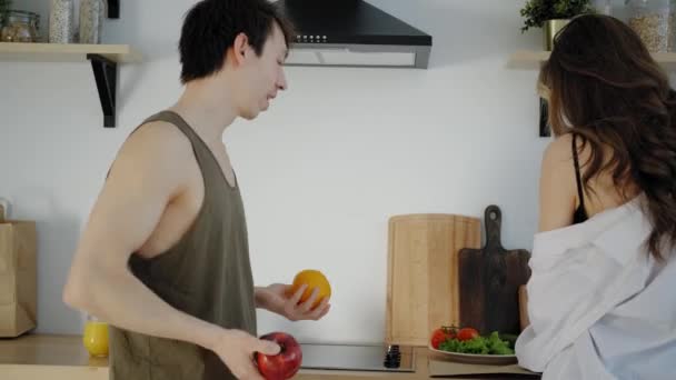 Man juggles and dancing with fruit, rejoice with his girlfriend. - Záběry, video