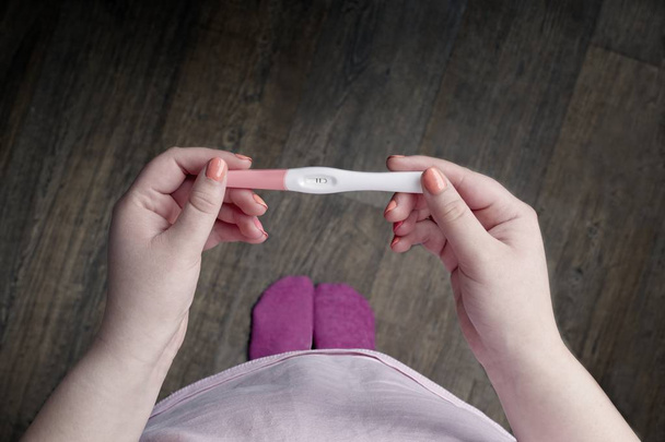 Το κορίτσι με το τρίο κάνει τεστ εγκυμοσύνης. Προσωπική προοπτική με χώρο αντιγραφής. - Φωτογραφία, εικόνα