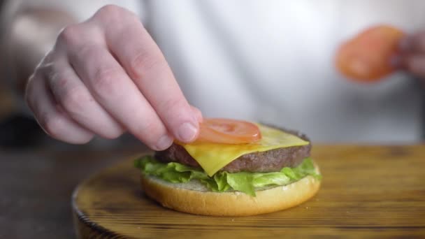 Chef kookt hamburger en zet vers gesneden tomaat erin, maken hamburgers in het Fast Food Restaurant, 4k UHD 60p ProRes HQ 422 - Video