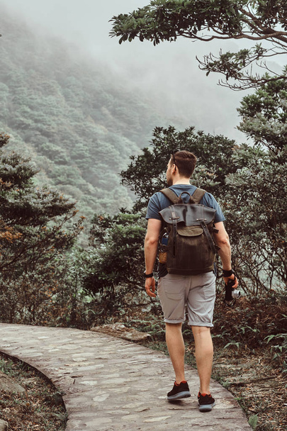 Sırt çantası olan adam güzel doğada taş yol tarafından yürüyor - Fotoğraf, Görsel