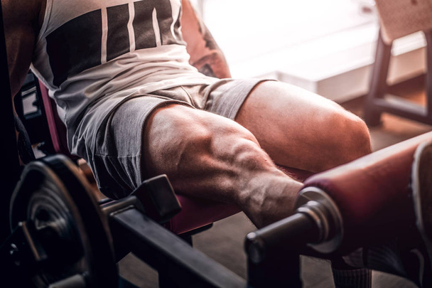 Homem musculoso forte está fazendo exercícios de pernas no aparelho de treinamento
 - Foto, Imagem