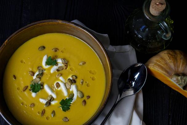pumpkin soup on a wooden background with olive oil, pumpkin, pumpkin seeds and cream cheese - Фото, зображення