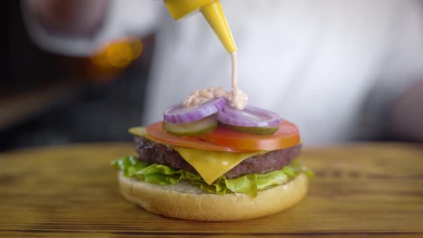 Şef sulu burger yapar ve içine baharatlı sos döker , fast food restoranda burger yapma, barbekü vurgers, 4k Uhd 60p Prores Hq 422 - Video, Çekim