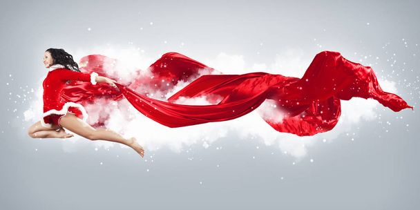 Happy smiling woman in red xmas costume jumping high - Фото, изображение