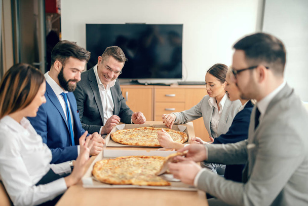 Uomini d'affari seduti in sala riunioni a mangiare pizza a pranzo
. - Foto, immagini