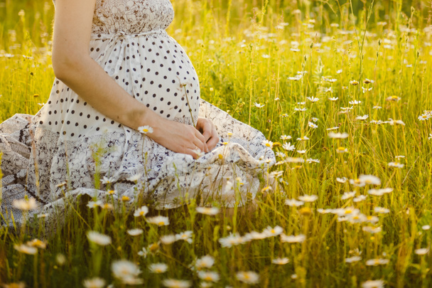 Close up of pregnant belly in nature. Pregnant girl in the sunset, pregnant woman relaxing outside in the park - Photo, Image