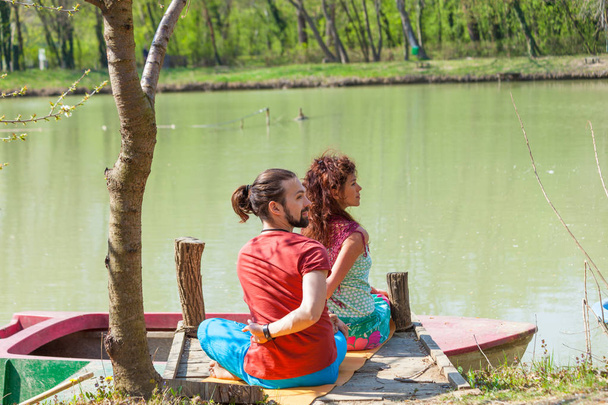 jovem homem e mulher praticam ioga ao ar livre junto ao lago sunny summ
 - Foto, Imagem